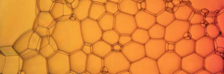 The surface of the bubbles. Extreme close-up of soap foam structure on orange gradient background....