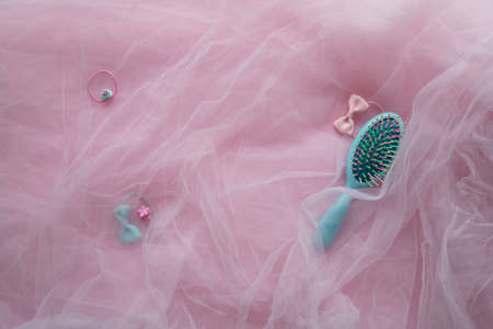 Hair accessories. Blue brush and pink hair bands on a background of pink fabricの写真素材