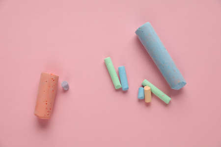 Colored pieces of chalk on a pink background. Crayons for drawing and creativity for childrenの写真素材