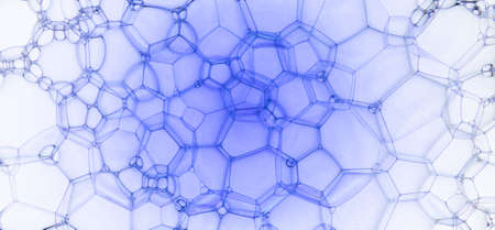 The surface of the bubbles. Extreme close-up of soap foam structure on white and blue. Cosmetic background, wallpaper. Web banner formatの写真素材