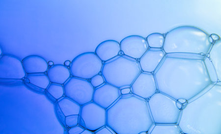 The surface of the bubbles. Extreme close-up of soap foam structure on blue water surface. Cosmetic...