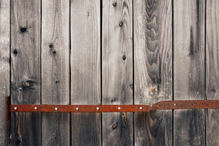 Old wood texture. Barn gate from aged pine boards with a rusty metal strip. Door hinges with rusty...