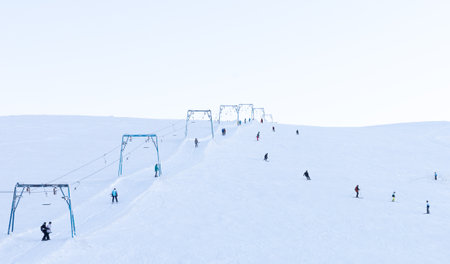 Skiing and snowboarding. A ski slope with a ski lift and small unrecognizable figures of people on a background of white snow, staffageの写真素材