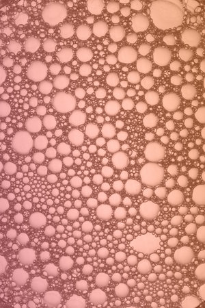 Extreme close-up of soap foam structure on peach and pink. Cosmetic background, the surface of the bubblesの写真素材
