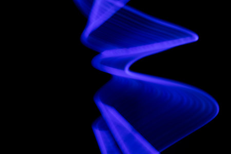Abstract neon background with copy space. Blue light waves on a black. Freeze light, long exposure