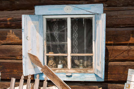 The window of the old wooden log house on the background of wooden walls