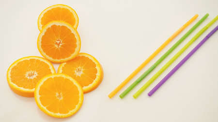 Orange slices and colorful juice straws.の写真素材