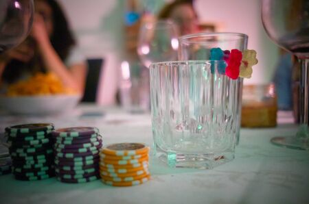 Late in the evening. A empty whiskey glass and a few poker chipsの写真素材