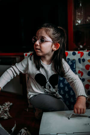 little girl with glasses opening a present on her birthdayの写真素材