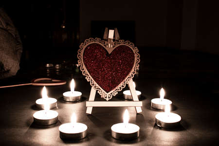 The scarlet wooden heart surrounded by candlesの写真素材