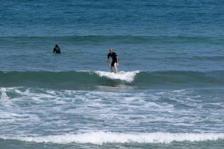 Guipuzkoa, Zarautz, Spain - 09, July, 2022: Group of surfers on the beaches of Zarautz.