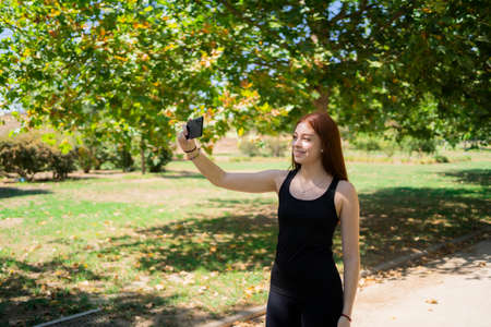 Young woman taking selfie in the park while exercisingの写真素材