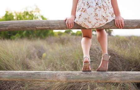 young woman sitting on a railing contemplating a fieldの写真素材