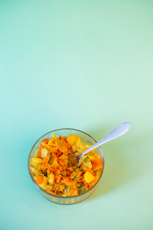 Vegetable salad in glass bowl with spoon on green background.の写真素材