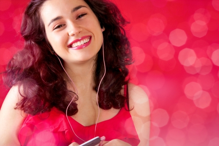 Happy young woman listening to music on mobile with pink earphonesの写真素材