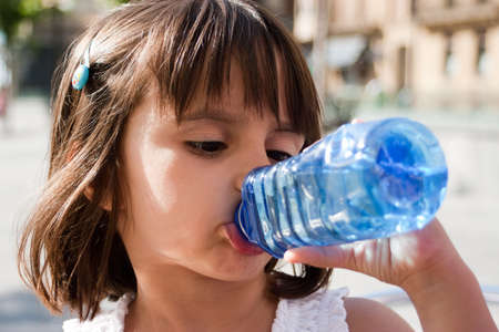 Thirsty little girl drinking water from a plastic bottle in a summer day  Outdoors の写真素材