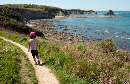 Little girl walking along a path on a cliff overlooking the sea  Loya Bay and Pirate Island in Hendaye の写真素材