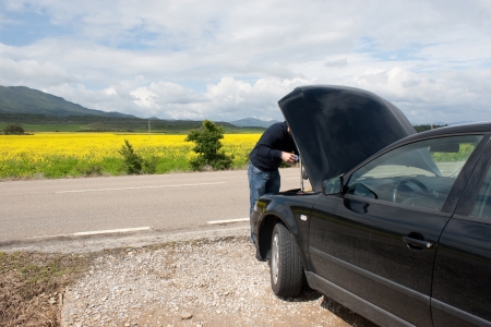 Man with his car parked beside the road for a mechanical problemの写真素材