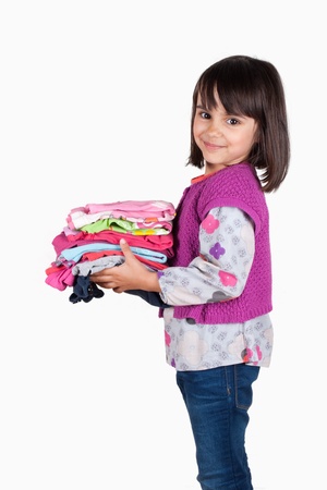 Happy little girl holding a stack of shirtsの写真素材
