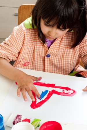 Concentrated little girl painting with fingersの写真素材