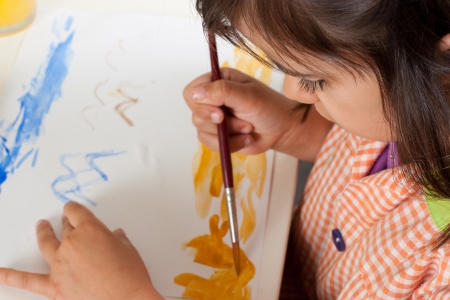 Little girl painting with paintbrush and watercolor  Focus in the eye の写真素材