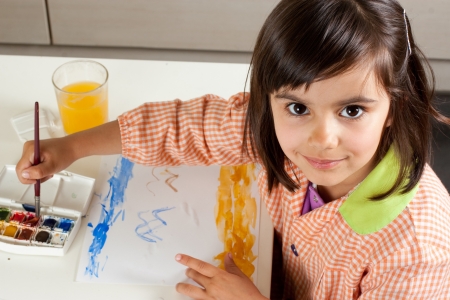Cute little girl painting a landscape with watercolors  Looking at camera の写真素材
