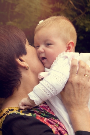 Grandmother holding and kissing tenderly her granddaughter  Warm effect edition の写真素材