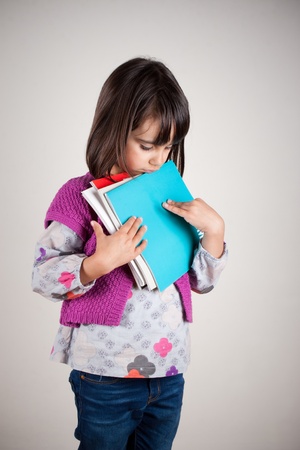 Sad little girl loking down holding her new school booksの写真素材