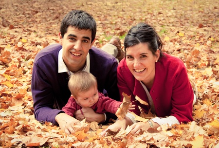 Happy family at the park in autumn lying in the fallen leavesの写真素材