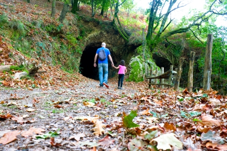 Father and daughter walking in the forest in autumn approaching a tunnelの写真素材