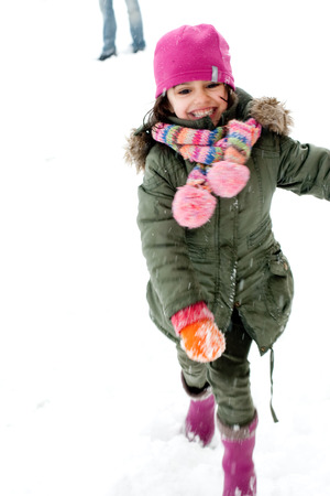 Happy little girl running away from snowballs, in the legs of his father  Blurred の写真素材