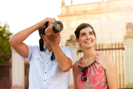 Attractive couple of tourists visiting the city and taking pictures of the monumentsの写真素材