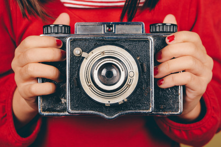 Retro medium format camera in little girl hands with red nails  Some film grain and vintage effect addedの写真素材