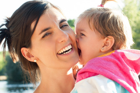 Cute baby girl biting his pretty mother laughing after bathing. Real people.の写真素材