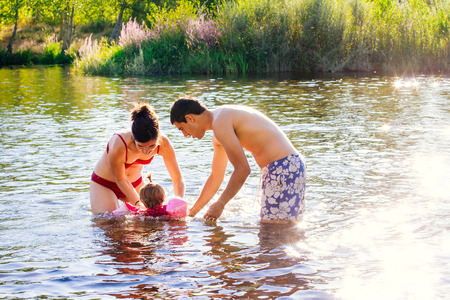 Atractive young couple playing with baby in the water of a riverの写真素材