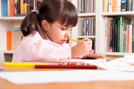 Cute little girl in uniform doing home workの写真素材