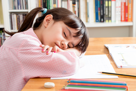 School girl sleeping while doing homeworkの写真素材