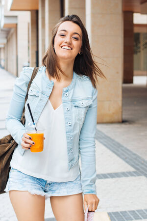 Urban happy and healthy girl walking down the street with a fruit smoothieの写真素材