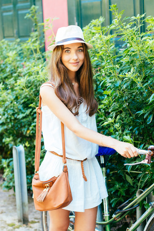 Beautiful and stylish girl wiyh hat parking her bicycleの写真素材