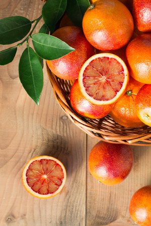 Bloody oranges in a basket on a wooden tableの写真素材