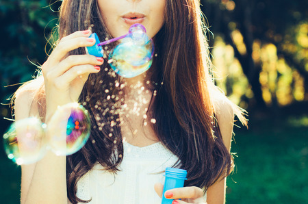 Girl blowing bubbles outdoor. Focus on lips.