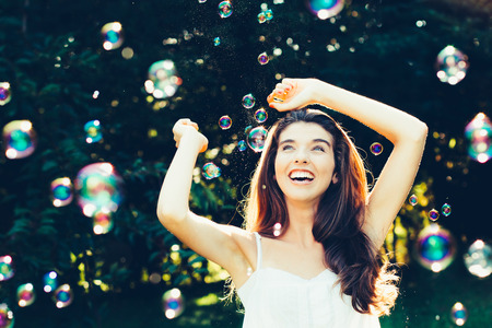 Beautiful young woman having fun with bubbles outdoors