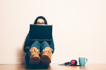 Girl sitting on the floor with a laptop looking at screen concentrated. Filter effect added.