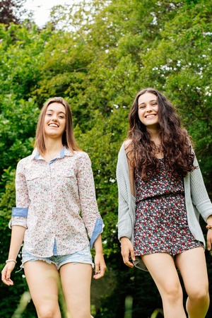 Cute and funny girl friends walking in natureの写真素材