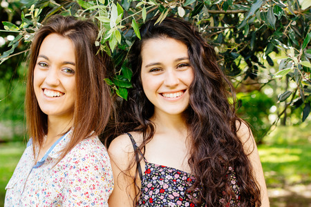 Cute and funny girl friends under an olive treeの写真素材