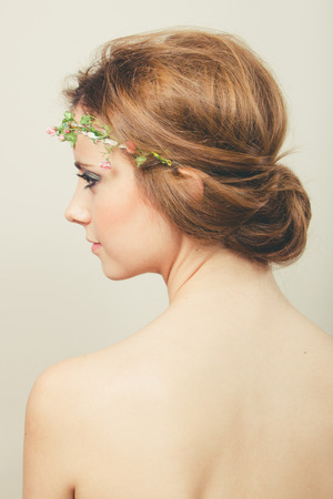 Beautiful blond woman with hair tied back with a tiara of artificial rosesの写真素材