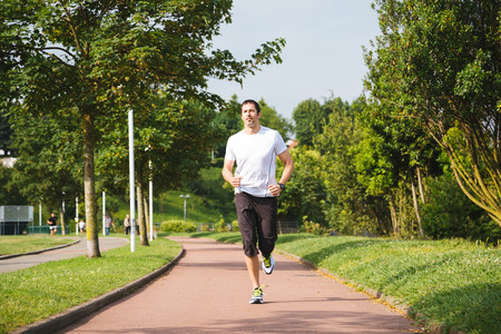 Man running on a track in a sunny day