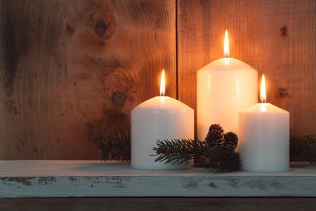 Christmas candles and fir branches over wooden backgroundの写真素材