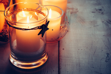 Christmas candles with a tied star on a wooden background at nigthの写真素材