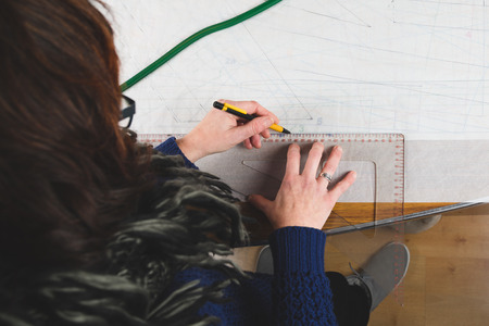 Hands of seamstress drawing templates in tracing paper using rulesの写真素材